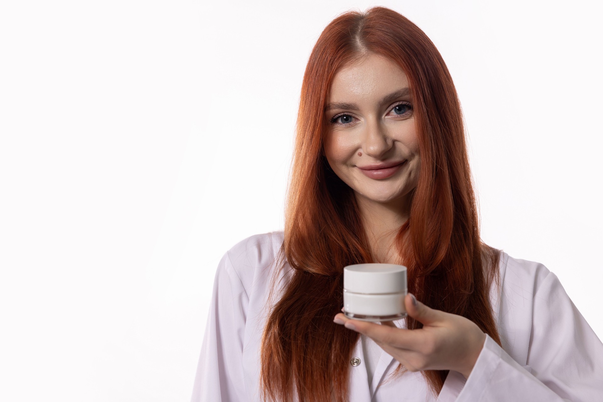 Eine lächelnde Frau in einem professionellen Laborkittel hält elegant eine Hautpflegecreme in der Hand